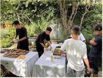 Equipo de Burgerset preparando hamburguesas sobre mesas montadas en el jardín de una casa, con invitados acercándose al mesón.