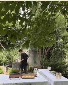 Estación de Burgerset montada con mesas y manteles blancos en el jardín de una casa.
